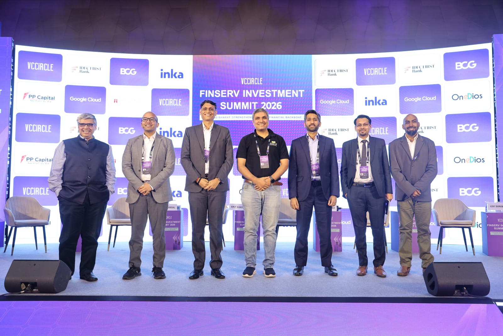 The seven speakers standing together in front of the summit backdrop at the end of the session.